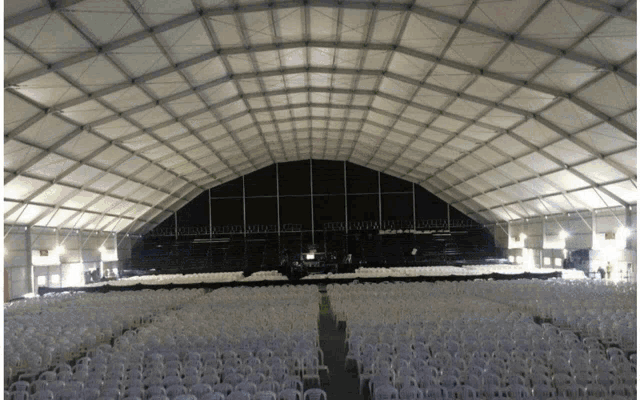 a large white tent with rows of white chairs