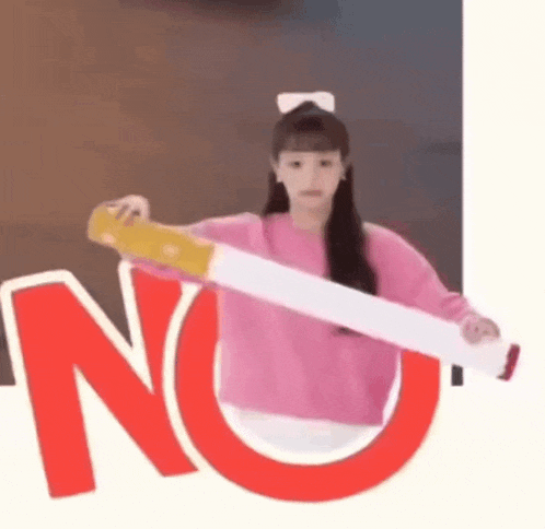 a girl in a pink sweater is holding a cigarette in front of a no sign .