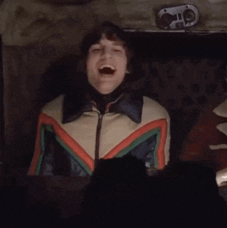a man in a colorful jacket is yawning in a car