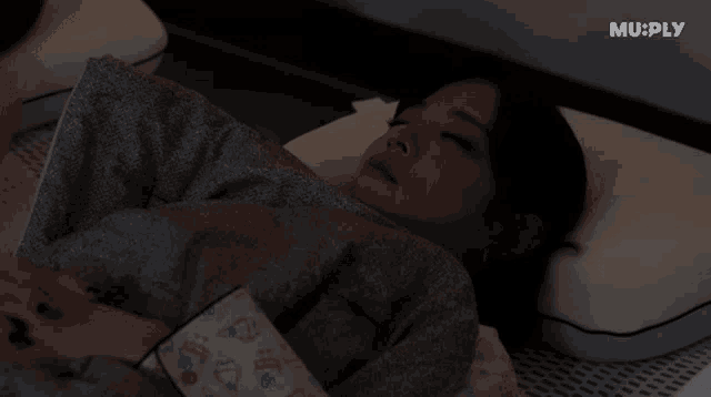 a woman laying on a bed with muply written on the bottom right