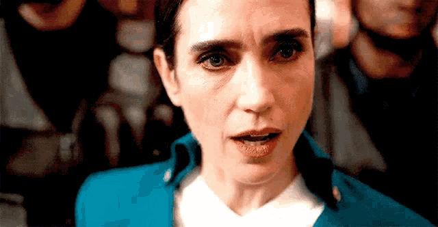 a woman in a blue jacket and white shirt is looking at the camera .