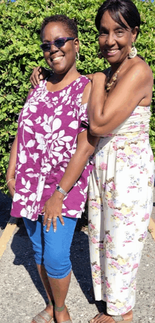 two women are posing for a picture and one is wearing a floral dress