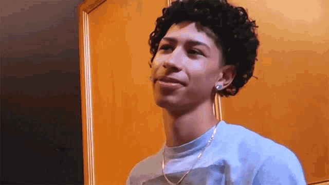 a young man with curly hair is wearing a blue shirt