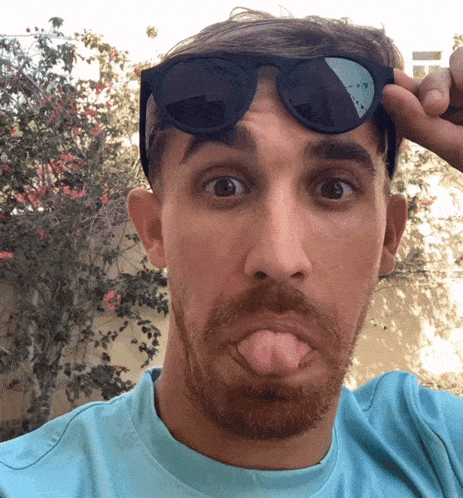 a man wearing sunglasses making a funny face with his tongue out