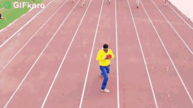 a man is running on a track holding a red heart shaped object .