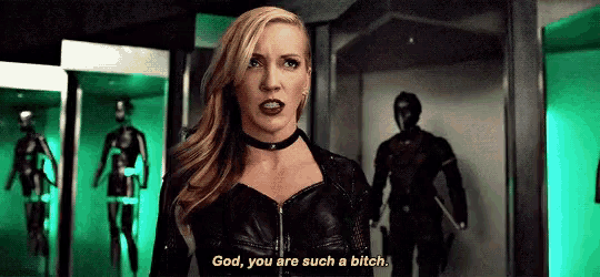 a woman in a black leather jacket is standing in a room talking to a man .