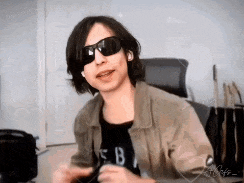 a young man wearing sunglasses and a jacket with the letter b on his shirt