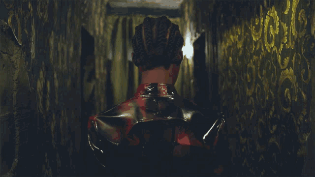 a woman in a red and black latex outfit is standing in a dark hallway