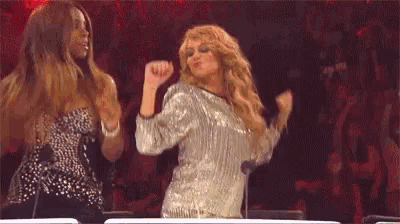 two women are standing next to each other on a stage in front of a microphone .