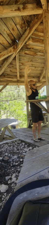 a man is standing under a wooden structure with his arms up