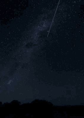 a shooting star flies through the night sky