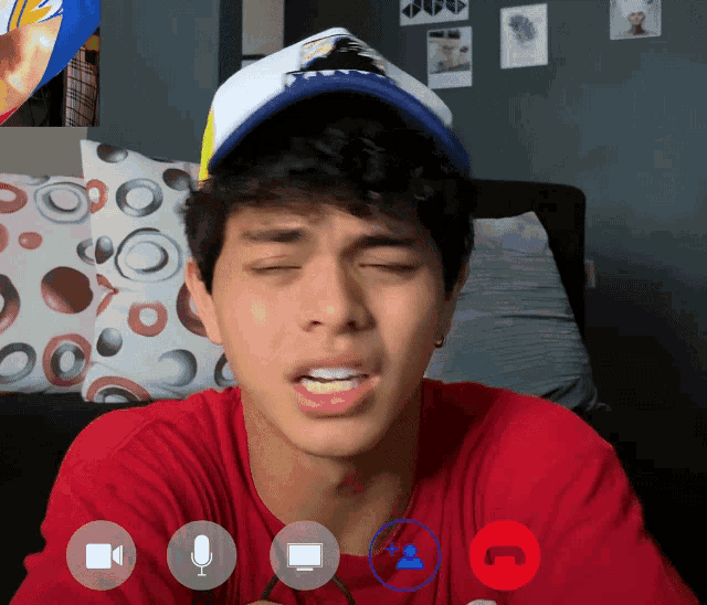 a young man wearing a hat with the letter t on it is having a video call