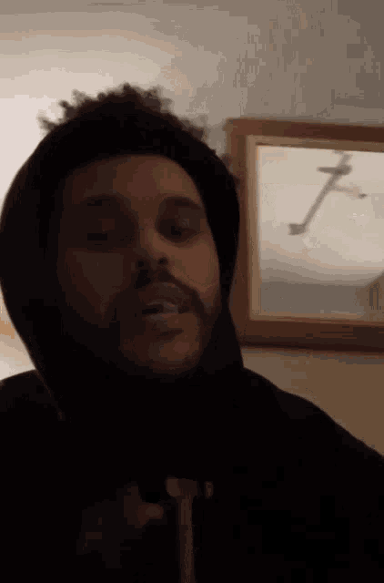 a man wearing a black hoodie with the letter t on the front