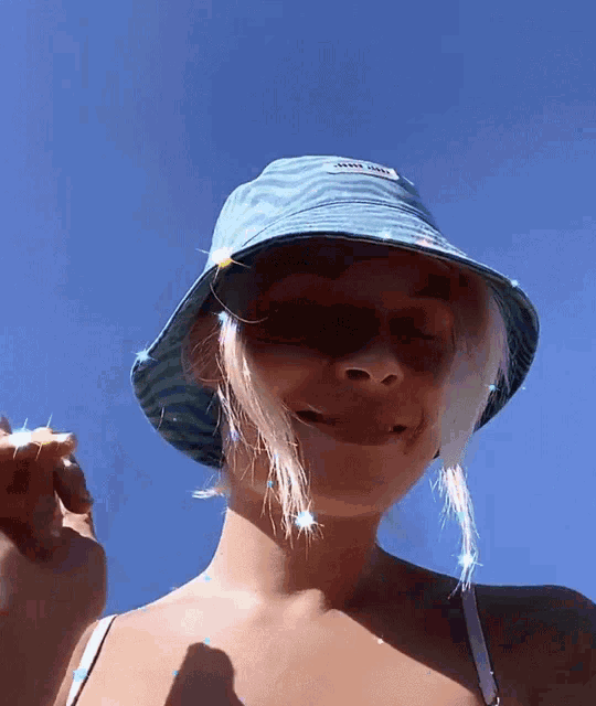 a woman wearing a blue bucket hat with the word miu miu on the front