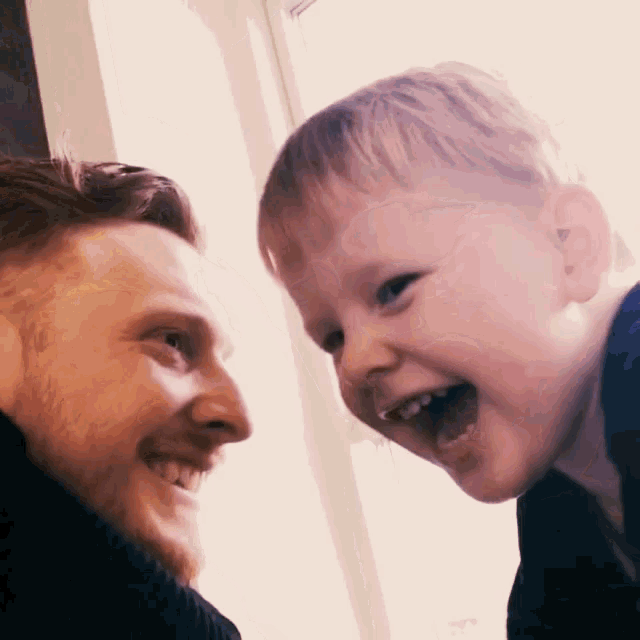 a man and a child are smiling at each other and looking at each other