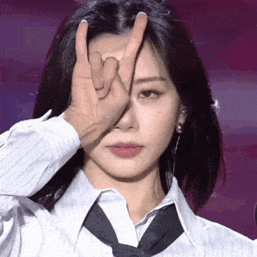a woman in a striped shirt and tie is making a devil horns sign with her hands