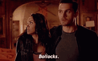 a man and a woman are standing next to each other in a living room . the woman is saying bollocks .