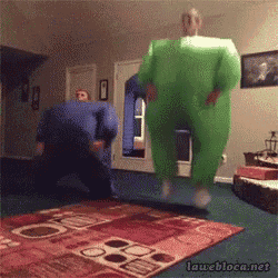 two men in green jumpsuits are jumping in a living room ..