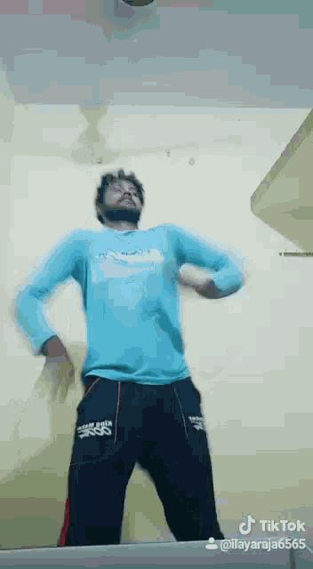 a man in a blue shirt and black pants is dancing on a tik tok video