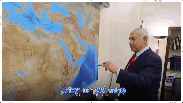 a man in a suit and tie is pointing at a map of the world in hebrew