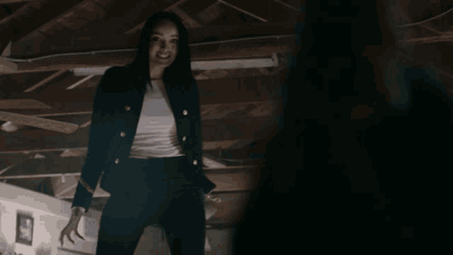 a woman in a black jacket and black pants stands in the dark