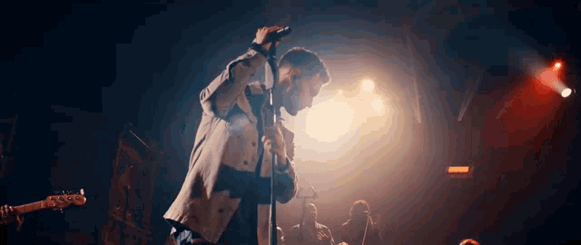 a man is singing into a microphone on stage in front of a crowd