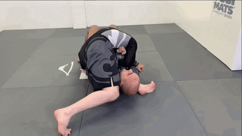 a man is laying on a mat in front of a wall that says mats on it