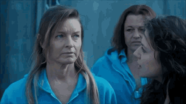 a woman in a blue sweatshirt talks to two other women
