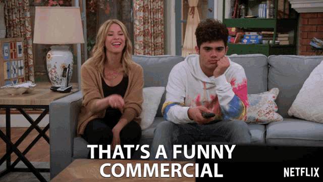 a man and a woman are sitting on a couch watching netflix