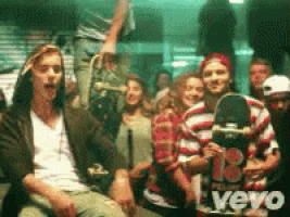 a group of people are gathered in a room and one of them is holding a skateboard that says vevo