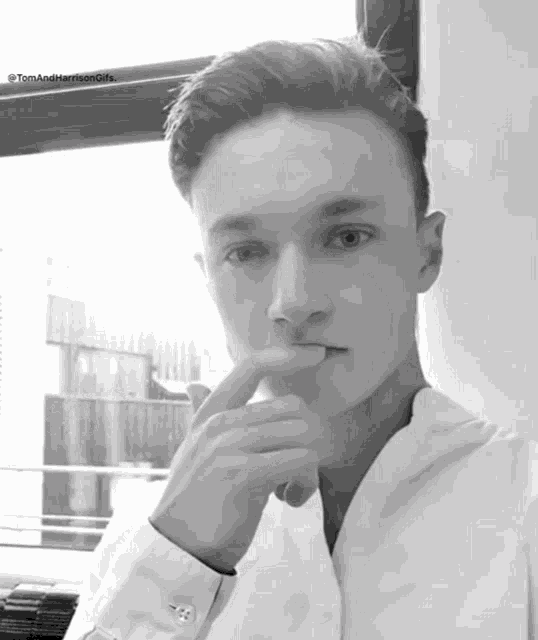 a black and white photo of a young man with the words tom and harrison gifs below him