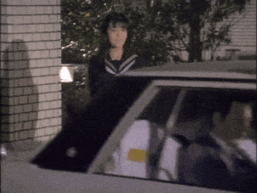 a woman in a school uniform is standing in front of a car