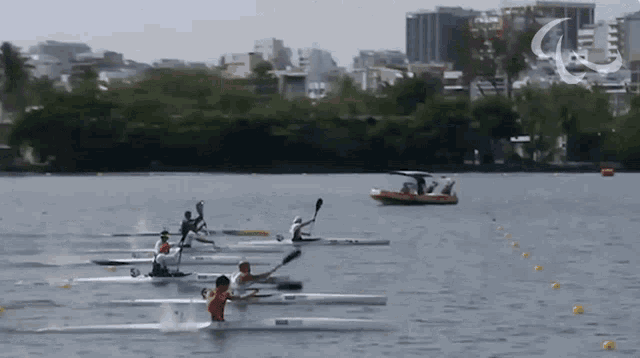 a group of people are rowing kayaks in a lake and one of them is wearing a red shirt with the letter r on it