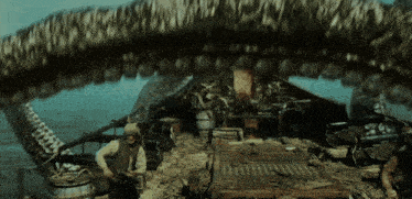 a man sits on a boat with a giant snake coming out of it 's mouth