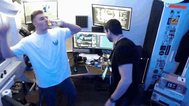 a man drinking from a bottle while another man stands in front of a computer monitor with the word legion on it