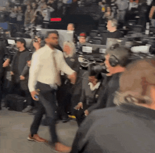a man in a white shirt is walking in a crowd of people