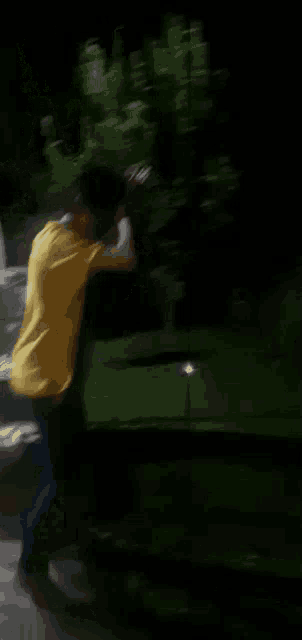 a blurry picture of a man in a yellow shirt standing next to a green car