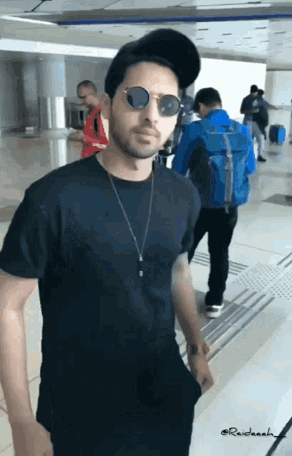 a man wearing sunglasses and a black shirt has the name raidaah written on the bottom of his shirt