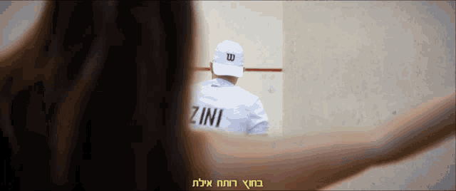 a man wearing a white shirt with the word zini on it