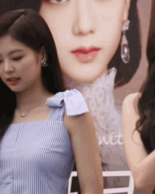 a woman in a blue striped dress is standing in front of a picture of another woman