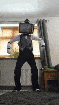 a man in a suit with a tv on his head is dancing