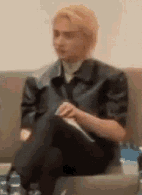 a person is sitting on a couch with their legs crossed and a bottle of water in front of them .