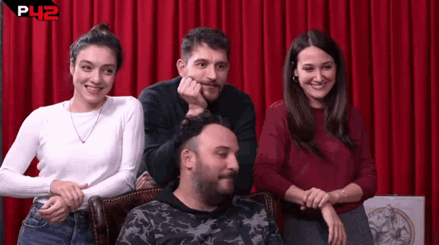 a group of people are sitting in front of a red curtain with the letters p42 on it