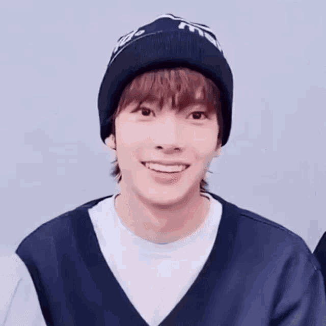 a young man wearing a beanie and a vest is smiling .