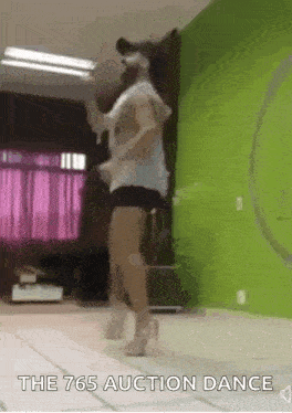 a woman is dancing in a room with a green wall and a hula hoop .