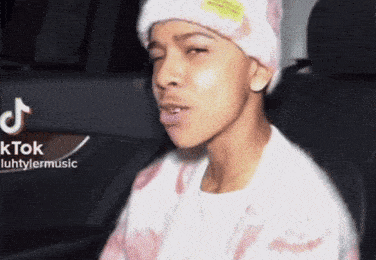 a young man wearing a beanie and a sweater is sitting in a car .
