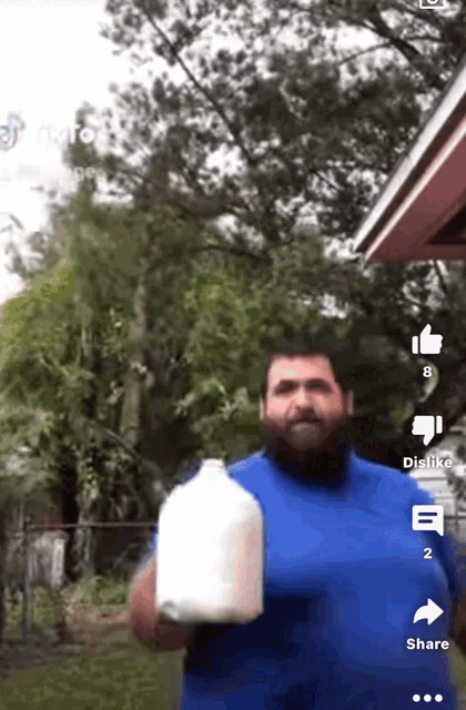 a man in a blue shirt holds a gallon of milk