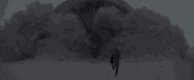 a man is walking through a cloud of smoke in a dark room .