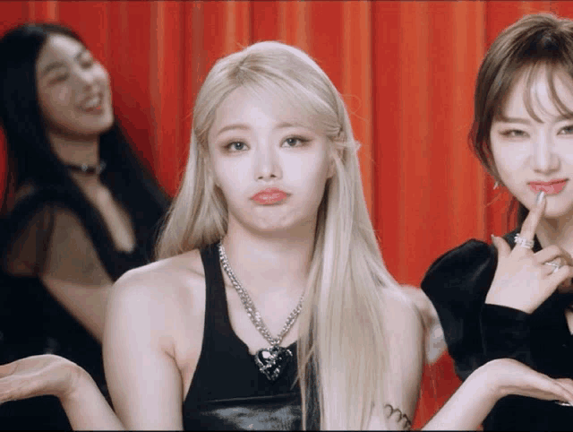 a woman with blonde hair is making a funny face in front of two other women