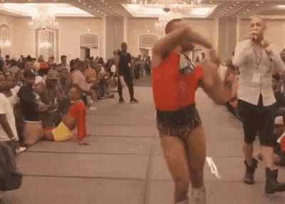 a man in a red shirt and shorts is dancing on a stage in front of a crowd .